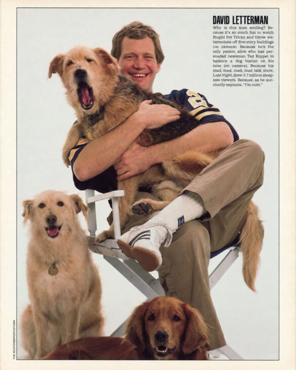 David Letterman smiling while seated with three dogs for a 1987 magazine feature about his “Stupid Pet Tricks” segment on Late Night with David Letterman.